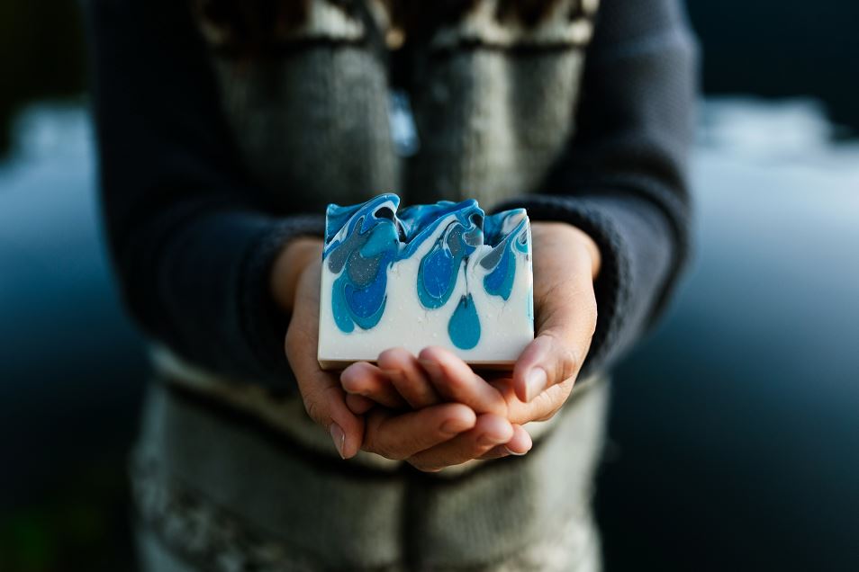 Soft image of RavenSong Soap held in hands with water in background