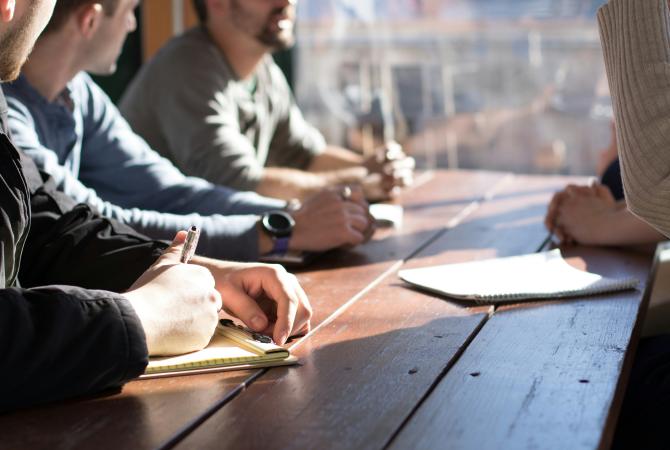 3 people interviewing another in a casual environment beside a window