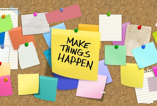 cork bulletin board with yellow post it note that says make it happen