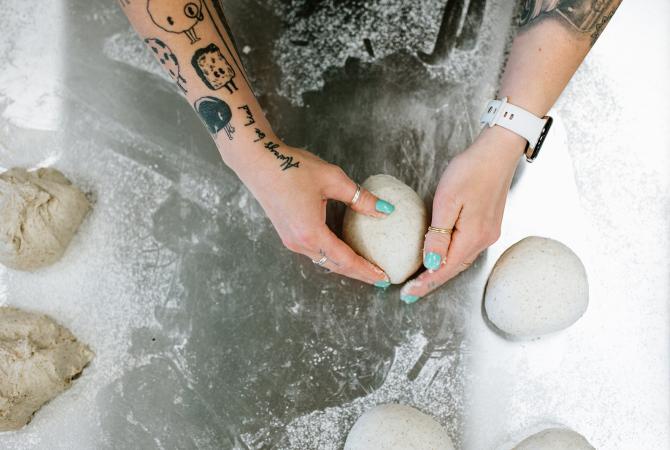 two hands forming a ball of bread dough